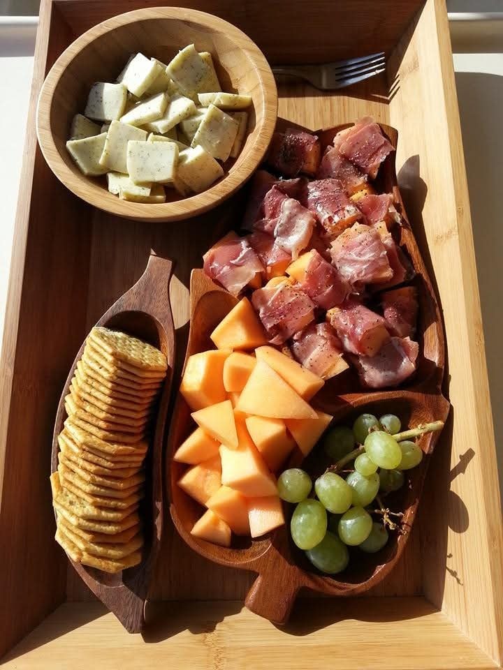 Overhead view of a beautiful charcuterie tray with prosciutto-wrapped melon, grapes, crackers and herb cheese