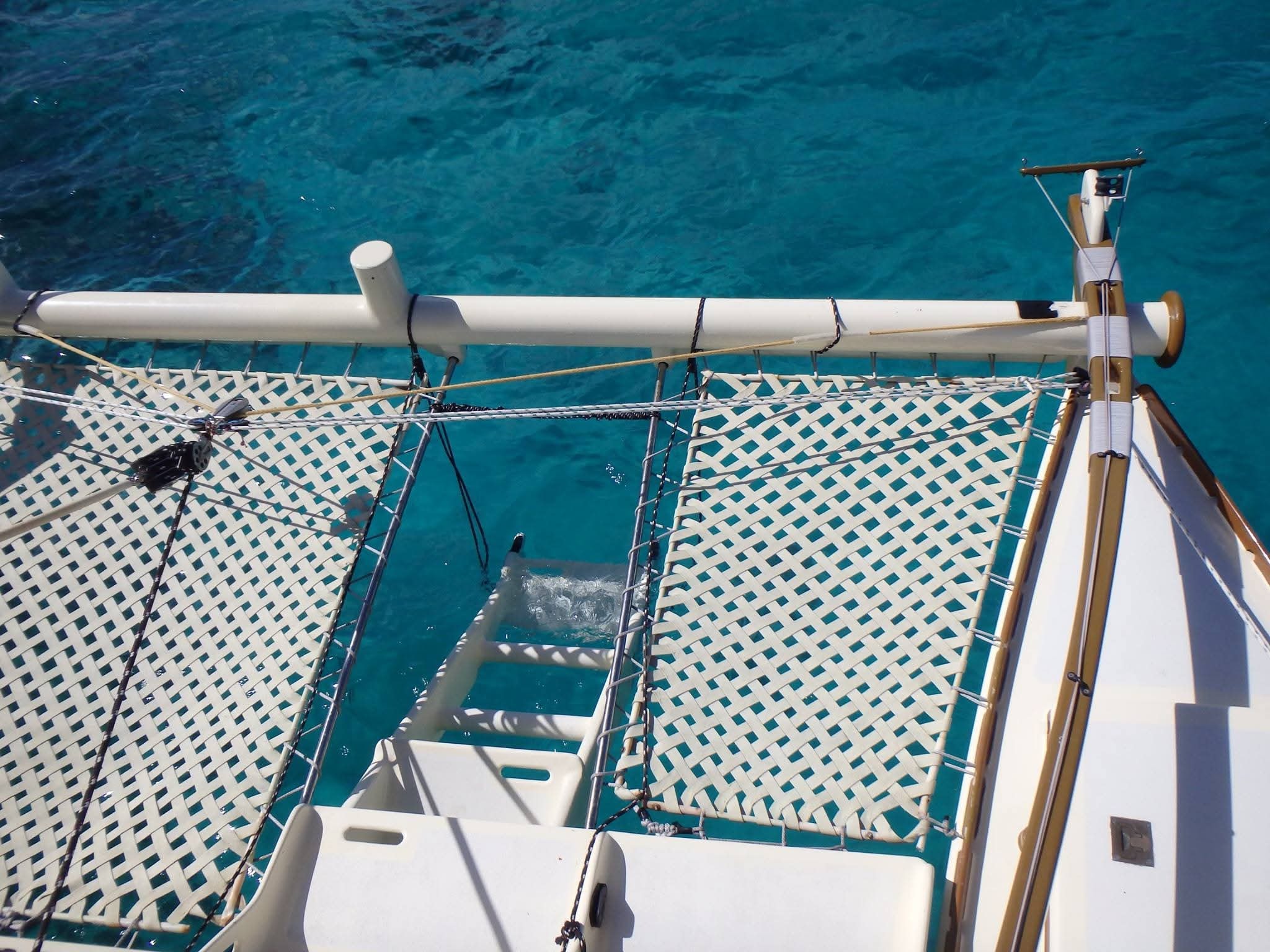 Looking down from the Mahiya mast over the trampoline nets and swim ladder into brilliant turquoise water below