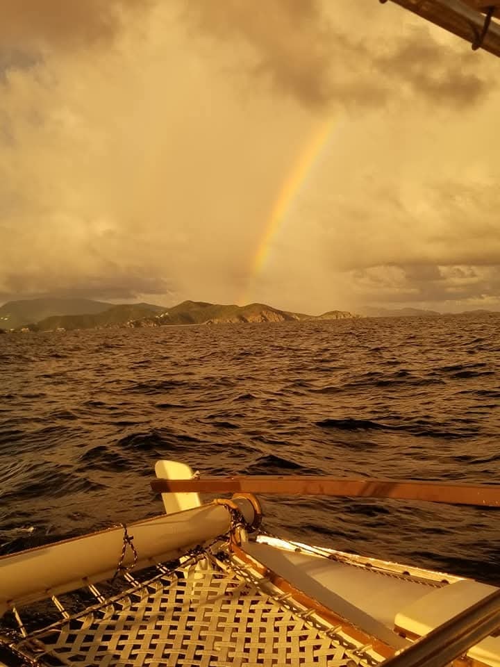 Rainbow touching the Virgin Islands mountains in golden-hour light from the deck