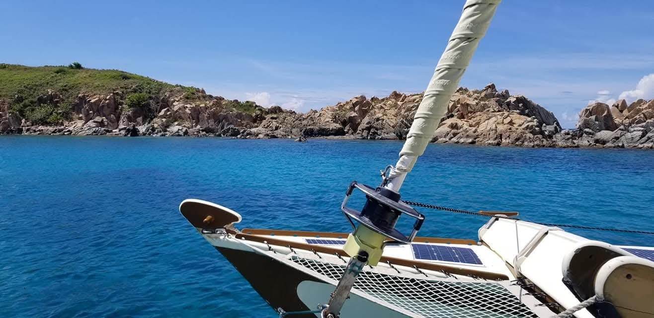 Mahiya anchored in a brilliant turquoise cove with rocky VI coastline