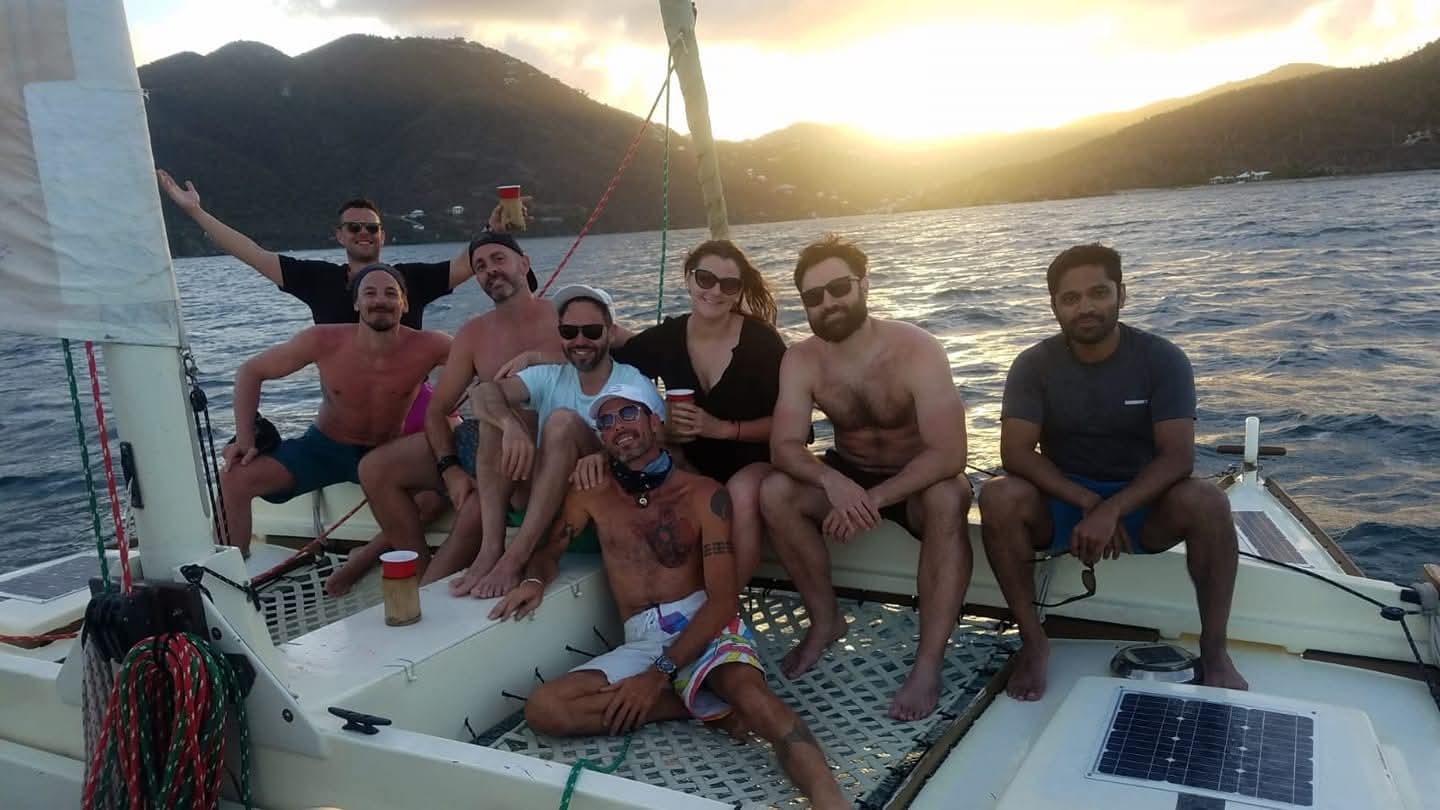 Group of eight happy guests on the Mahiya net at golden sunset with VI mountains behind