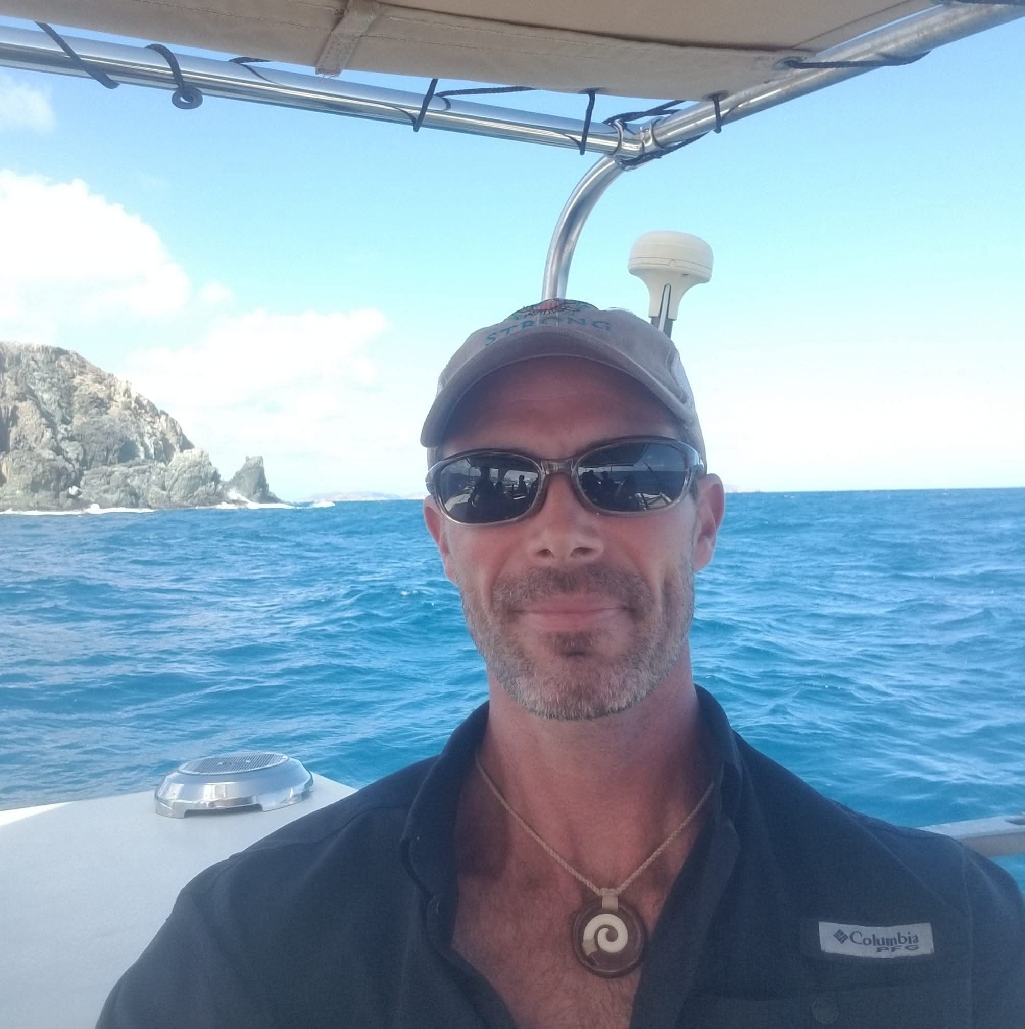 Captain Karl portrait selfie on the water with dramatic rocky VI cliffs behind