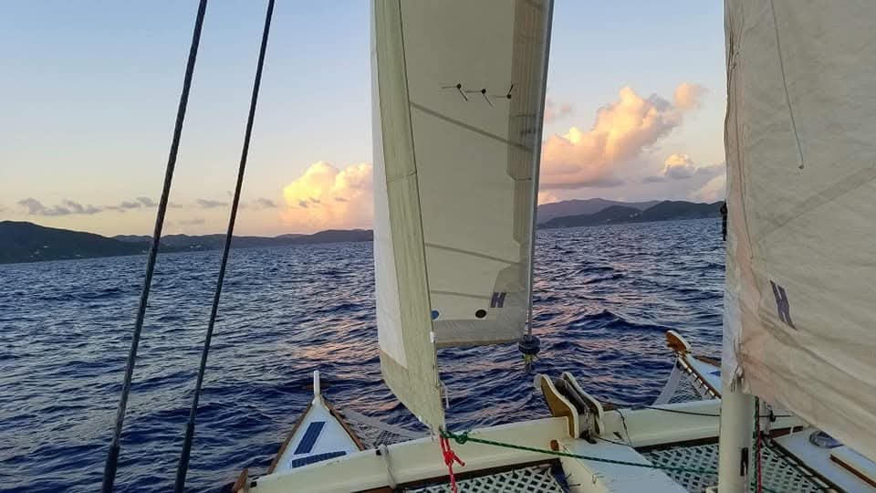 Looking forward through the Mahiya sails at dusk with VI mountains in the distance
