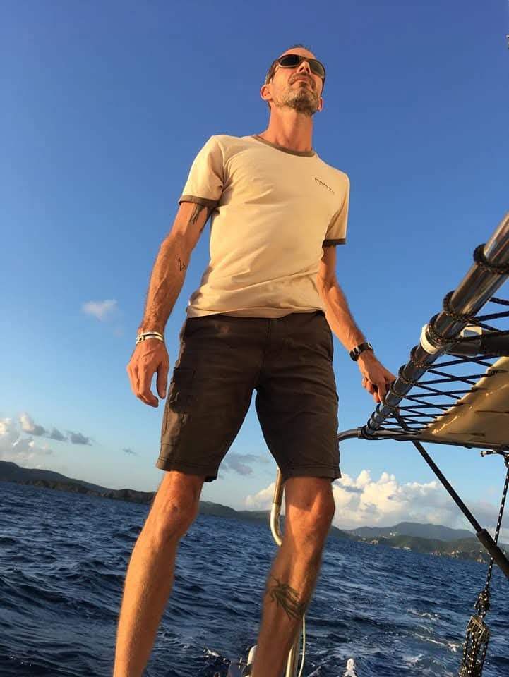 Captain Karl low-angle hero portrait on the Mahiya with blue sky and VI islands behind
