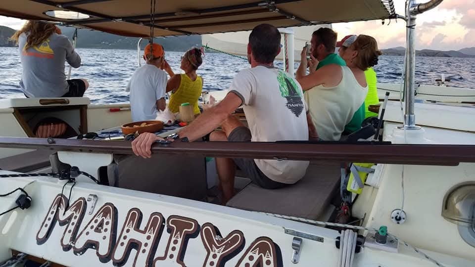 Guests aboard the Mahiya watching the sunset, boat name clearly visible on the hull