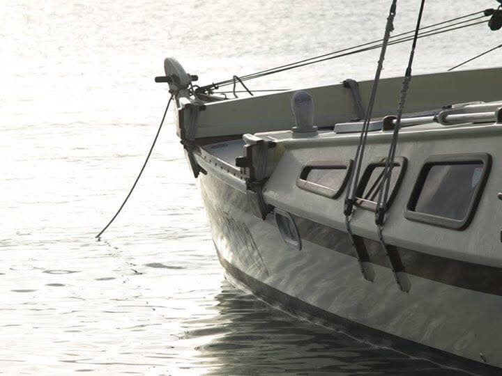 Close-up of the Mahiya bow on calm misty water at dawn, rigging and porthole details visible
