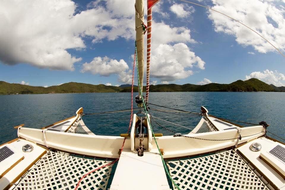 Wide-angle view from the Mahiya bow looking forward through the rigging at lush green VI islands and blue sky