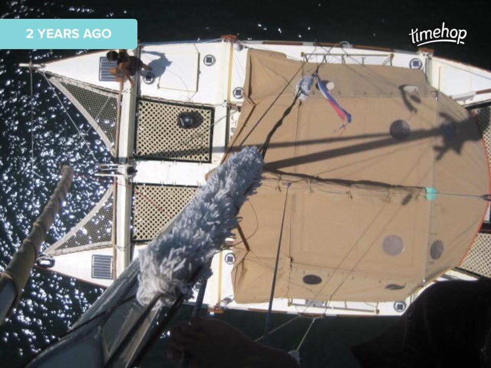 Aerial view looking straight down at the Mahiya catamaran deck on sparkling open water, person visible on deck