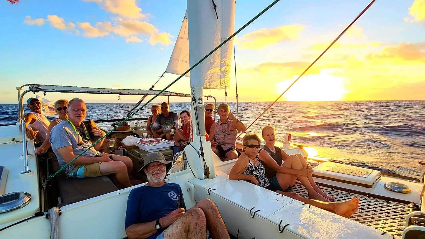 Happy group of guests aboard the Mahiya at golden sunset