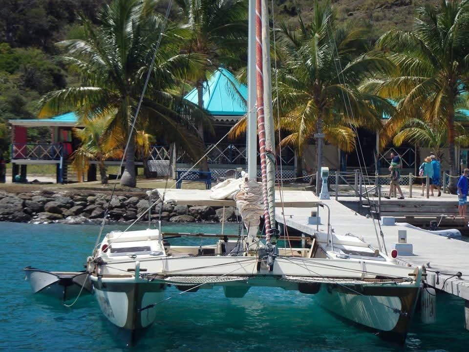 Mahiya catamaran docked at a tropical pier with palm trees and colorful Caribbean buildings behind