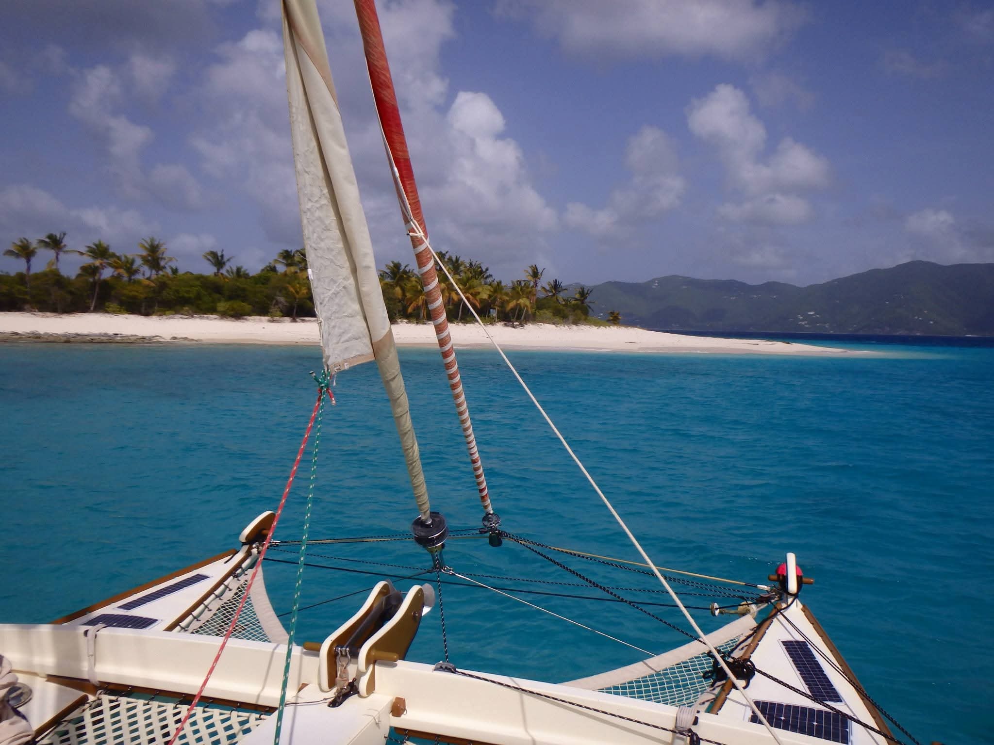 View from the Mahiya bow looking forward at a stunning white sand beach and palm trees in brilliant turquoise water
